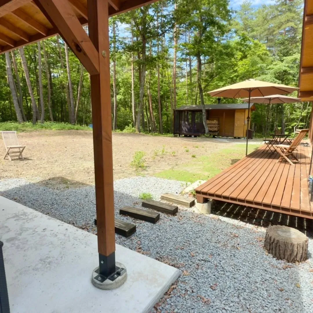 森の中に静かに佇む建物と、その周囲に広がる屋外スペースが、自...